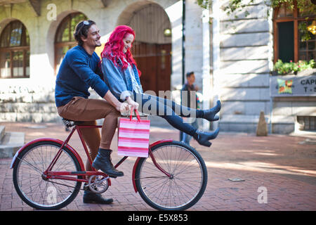 Giovane donna con seduta su fidanzati un manubrio di bicicletta, Cape Town, Sud Africa Foto Stock