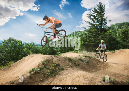 Due amici di sesso maschile di BMX di equitazione e mountain bike sulla pompa rurale via Foto Stock