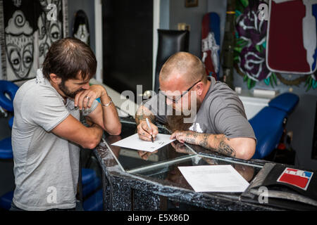 Artista redazione tattoo idee con un client Foto Stock