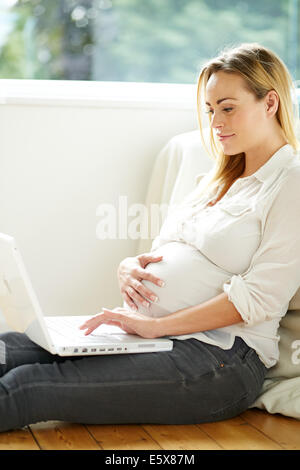 Donna incinta usando il computer portatile Foto Stock