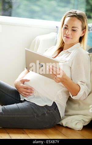 Donna incinta tramite iPad Foto Stock