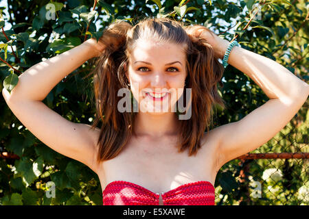 Ritratto di giovane donna bella bionda in natura, toccando i suoi capelli tails Foto Stock