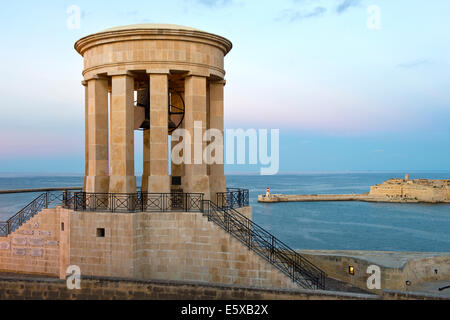 Assedio Bell Memorial affacciato sul Porto Grande di La Valletta a al crepuscolo, Valletta, Malta Foto Stock