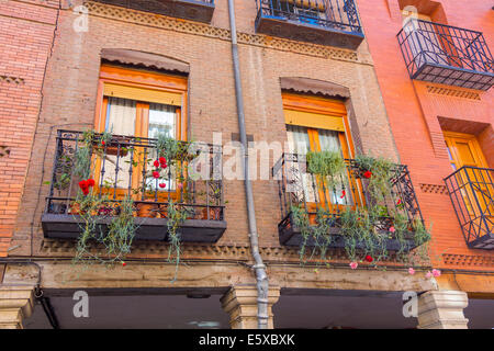 Balconi con fiori in una vecchia casa di mattoni Foto Stock