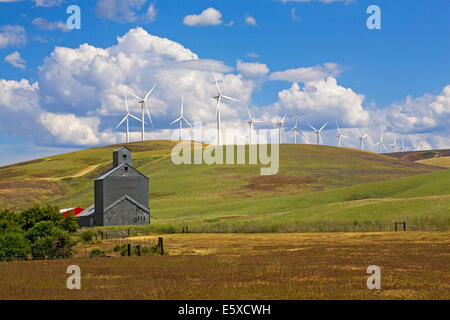 Una fattoria e grano silo oscurato dalle turbine eoliche in remoto Impero Palouse regione, di allevamento e di produzione del frumento regione orientale di Washington. Foto Stock