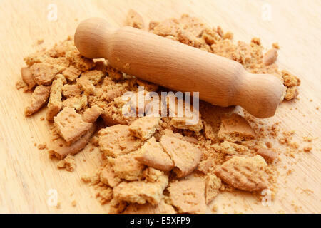 La frantumazione di biscotti digestivi in piccoli pezzi e briciole con una laminazione di legno pin Foto Stock