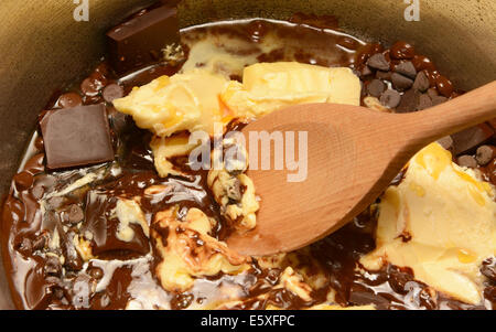 Fondere il burro e il cioccolato fondente insieme in una padella, mescolando con un cucchiaio di legno Foto Stock