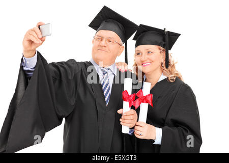 Coppia maschio e femmina in abiti di graduazione prendendo un selfie Foto Stock