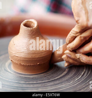 Potter mani rendendo in argilla sulla ruota di ceramiche. Potter fa sulla ruota in ceramica pentola di creta. Foto Stock