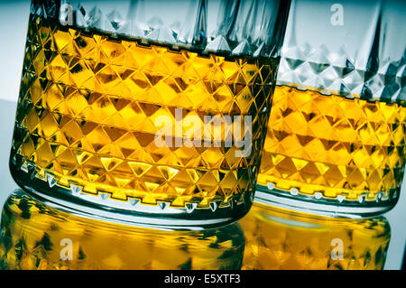 Primo piano di alcuni lowball occhiali con il whisky su una superficie riflettente Foto Stock