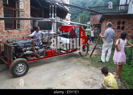 Dexing, Cina. Il 7 agosto, 2014. Agosto 07: Jiang Changgen si prepara per la prova di volo a Dajia village il 7 agosto 2014 in Dexing, Jiangxi provincia della Cina. Il 52-anno-vecchio Changgen Jiang ha trascorso due anni e 100.000 yuan (16,200 USD) rendendo il coassiale elicottero. L'elicottero è lunga 4 metri, 2,65 metri di altezza e pesa 900 kg. La sua lama del rotore è di 8 metri di lunghezza. Jiang ha cercato più di dieci minuti, ma non vi riuscì. Credito: SIPA Asia/ZUMA filo/Alamy Live News Foto Stock