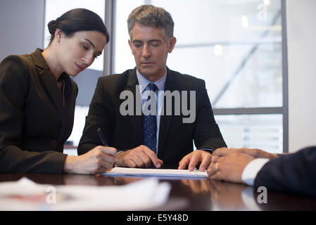 Business meeting, imprenditrice firma documento mentre associates osservare Foto Stock