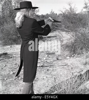 Immagine di stock di una bionda gunfighter femmina in 1860's outfit nel deserto. Foto Stock