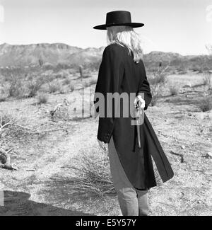 Immagine di stock di una bionda gunfighter femmina in 1860's outfit nel deserto. Foto Stock