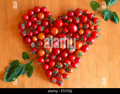 Pomodori ciliegia a forma di cuore con freccia realizzato da foglia Foto Stock