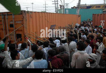 Lahore, Pakistan. 8 Ago, 2014. I manifestanti tentano di rimuovere un contenitore in Pakistan orientale di Lahore su Agosto 8, 2014. Il Pakistan polizia ha usato gas lacrimogeni gusci per disperdere il governo anti-manifestanti a Lahore tardi venerdì dopo che hanno sequestrato un autobus della polizia, testimoni e funzionari di detto. Centinaia di sostenitori di un leader religioso, Tahir ul Qadri si sono scontrati con la polizia dopo che avevano iniziato la rimozione dei contenitori dalle strade collocati dalle autorità per interrompere una manifestazione contro il governo il 10 agosto. Credito: Sajjad/Xinhua/Alamy Live News Foto Stock