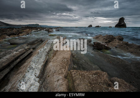 Nuvole temporalesche su Mupe Bay all'alba Foto Stock