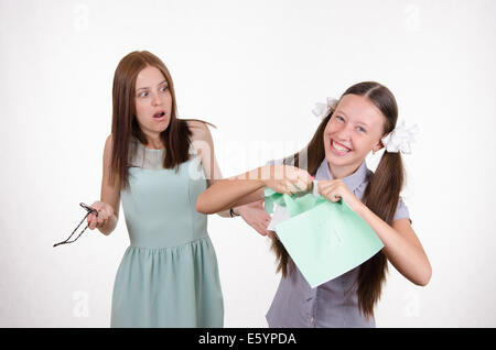 Schoolgirl divertendosi di strappare il notebook nella parte anteriore di un insegnante arrabbiato Foto Stock