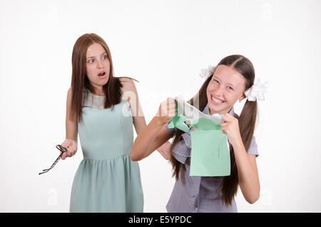 Schoolgirl divertendosi di strappare il notebook nella parte anteriore di un insegnante arrabbiato Foto Stock