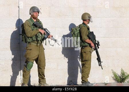 Soldati israeliani stand presso il pronto per le strade di Betlemme. Venerdì pomeriggio è stata dichiarata una rabbia in tutta la Cisgiordania. Nelle prime ore del mattino, dopo 8 A.m., la 72 Ore di cessate il fuoco tra Gaza e Israele si è conclusa e lottare contro la ripresa. Nelle prime ore della sera le forze israeliane hanno sparato e ucciso Ahmad Mohammad al-Qatar da al Amari Refugee Camp vicino a Ramallah, come le proteste hanno continuato nella solidarietà per la Striscia di Gaza in Cisgiordania. Oltre 40 persone sono rimaste ferite a Hebron durante le proteste. Nel frattempo, le incursioni aeree israeliane ucciso un bambino nel primo pomeriggio nel quartiere di Sheikh al-Radwan. Una moschea è stata Foto Stock