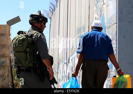 Un anziano uomo palestinese passeggiate ultimi soldati israeliani. Egli fa il suo modo a casa sua in Aida Refugee Camp che si trova vicino alla barriera di separazione. Venerdì pomeriggio è stata dichiarata una rabbia in tutta la Cisgiordania. Nelle prime ore del mattino, dopo 8 A.m., la 72 Ore di cessate il fuoco tra Gaza e Israele si è conclusa e lottare contro la ripresa. Nelle prime ore della sera le forze israeliane hanno sparato e ucciso Ahmad Mohammad al-Qatar da al Amari Refugee Camp vicino a Ramallah, come le proteste hanno continuato nella solidarietà per la Striscia di Gaza in Cisgiordania. Oltre 40 persone sono rimaste ferite a Hebron durante le proteste. Nel frattempo, le incursioni aeree israeliane ucciso Foto Stock