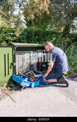 Ingegnere di lavoro per BT Openreach corregge le anomalie a banda larga ad un terminale sul lato della strada. Foto Stock