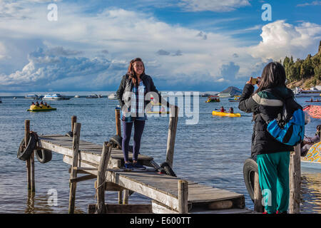 Una giovane donna di fotografare il suo amico femmina su un dock in legno sulla riva del lago Titicaca a Cochabamba, in Bolivia. Foto Stock