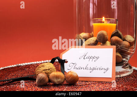 Bella felice ringraziamento impostazione tabella centrotavola con candela arancione e i dadi in vetro decorativo lampada di uragano vaso Foto Stock