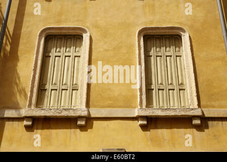 Due finestre con persiane in colore oro appartamento edificio, Verona, Italia. Foto Stock