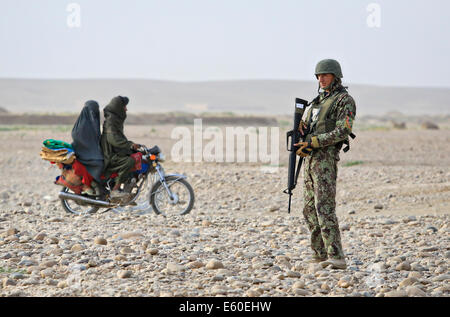 I civili afghani ride passato un esercito nazionale afghano soldato a un veicolo checkpoint Luglio 14, 2014 in Shekasteh Tappeh village, provincia di Helmand, Afghanistan, luglio 14, 2014. Foto Stock