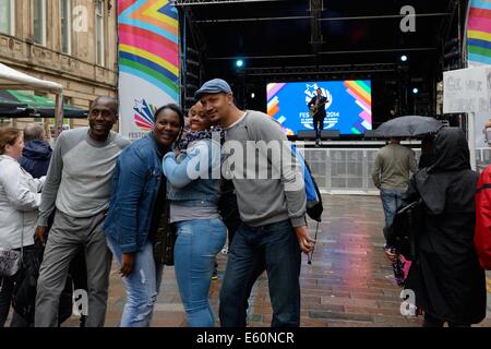 Tourist avente le foto scattate con il Merchant City palco del festival in un giorno di pioggia in Glasgow Foto Stock
