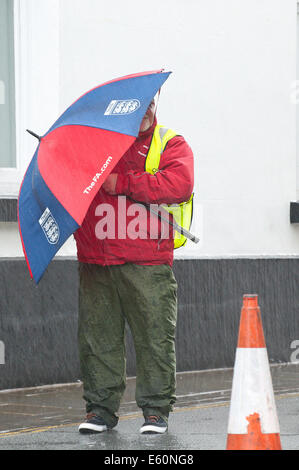 Brecon, Powys, Wales, Regno Unito. Il 10 agosto 2014. Uno Steward ospita dalla guida sotto la pioggia che colpisce Brecon l'ultimo giorno del trentesimo Brecon Jazz Festival. Credito: Graham M. Lawrence/Alamy Live News. Foto Stock