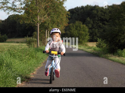 Bambina cavalcare la sua formazione bike all'aperto Foto Stock