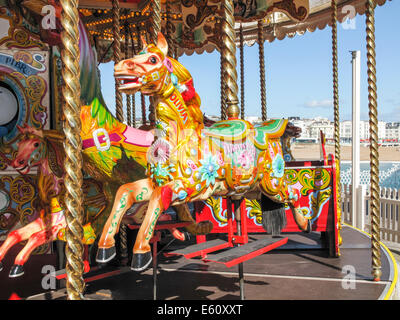 Vivacemente colorato cavalli su una Merry Go Round presso il parco di divertimenti sul molo di Brighton, Regno Unito su una soleggiata giornata estiva Foto Stock