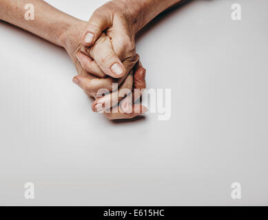 Senior donna di mani isolato su sfondo grigio. Le mani di un vecchio rilassato femmina con copia spazio. Pregando le mani. Foto Stock