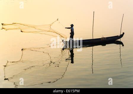 Pescatore in una barca nel lanciare un net, la luce del mattino, Lago Thaungthaman, Amarapura, Mandalay Division, Myanmar Foto Stock