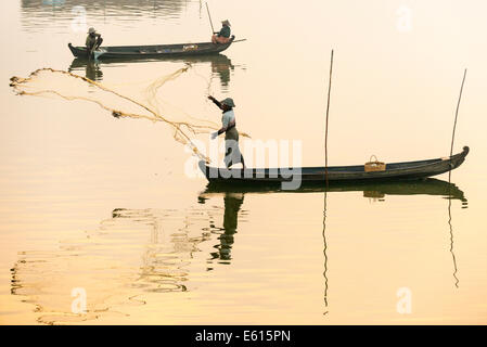 Pescatore in una barca nel lanciare un net, la luce del mattino, Lago Thaungthaman, Amarapura, Mandalay Division, Myanmar Foto Stock