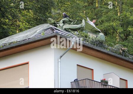 Bad Schwalbach, Germania. 11 Ago, 2014. Gli uomini di coprire un tetto che fu distrutta nella tempesta in Bad Schwalbach, Germania, 11 agosto 2014. Un forte tornado insieme con una tempesta di pioggia hanno provocato danni per milioni di persone. Numerose le vetture sono state danneggiate, tetti di case è venuto fuori e zone boschive distrutte. Foto: Fredrik von Erichsen/dpa/Alamy Live News Foto Stock