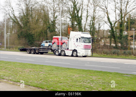 Un articolato caricatore basso portante due veicoli lungo la A23 road a Coulsdon, Surrey, Inghilterra Foto Stock