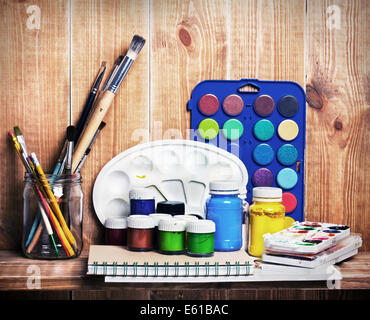 Pennelli acquerello, gouache e carta sono sul ripiano di legno Foto Stock