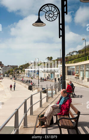 Regno Unito Inghilterra, Dorset, Lyme Regis. Marine Parade, visitatori sat nella luce del sole sul mare Foto Stock