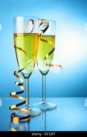 Due bicchieri di champagne con streamer oro su sfondo blu Foto Stock