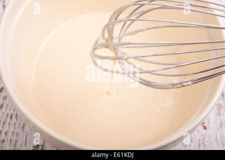 Pastella miscelati a mano mixer nel recipiente di miscelazione Foto Stock