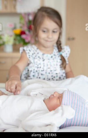 La ragazza (2-3) toccando il suo bambino la sorella (2-5 mesi) Foto Stock