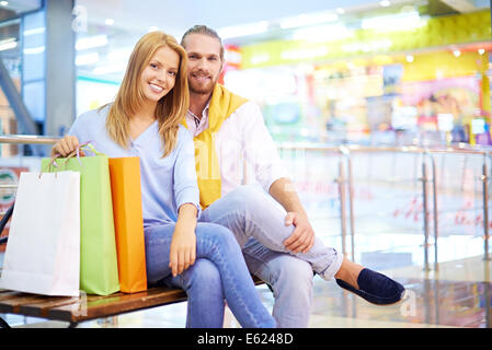 Coppia giovane seduto sulla panchina nel centro commerciale per lo shopping Foto Stock