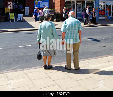 Una coppia di anziani tenendo le mani mentre si è in attesa di attraversare la strada a Cromer, Norfolk, Inghilterra, Regno Unito. Foto Stock