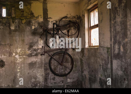 Un vecchio arrugginito bicicletta appesa al muro di una guerra mondiale 2 edificio di difesa in Tankerness, isole Orcadi, Scozia. Foto Stock