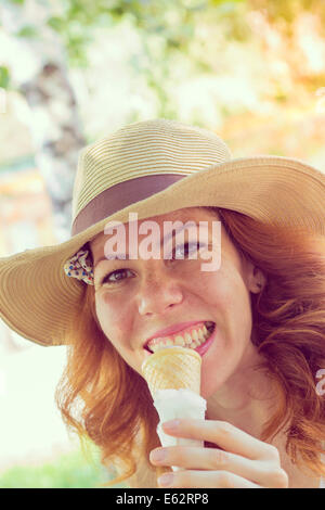 Bella ragazza a mangiare il gelato cono, vicino. In stile retrò immagini Foto Stock