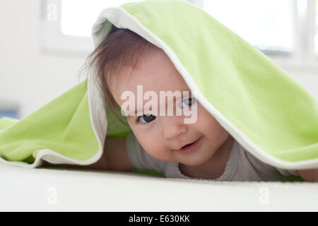 Bambina si nasconde sotto il bianco e il verde coperta Foto Stock