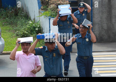 Quezon City, Filippine. 13 Ago, 2014. Poliziotti di coprire le loro teste durante un terremoto trapano in Quezon City, Filippine, e il agosto 13, 2014. Il terremoto trapanare mira a valutare la preparazione alle situazioni di emergenza le capacità di polizia. Credito: Rouelle Umali/Xinhua/Alamy Live News Foto Stock